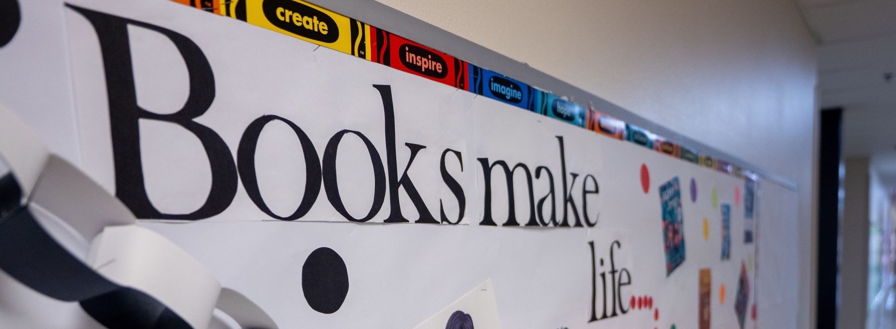 A bulletin board in the hallway that says Books make life colorful.