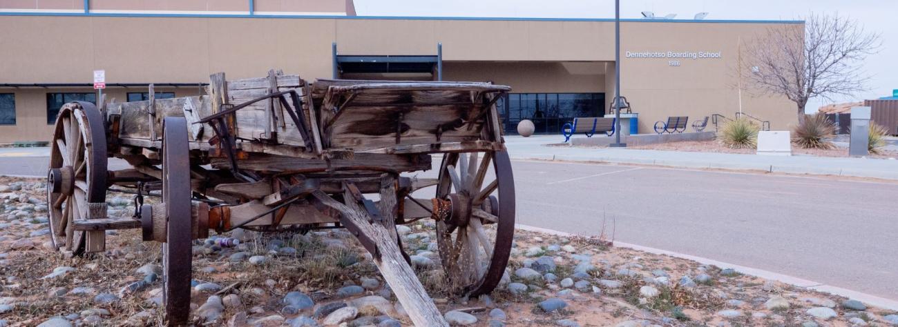 An old wooden wagon parked in front of the school, showcasing its rustic charm and historical significance.