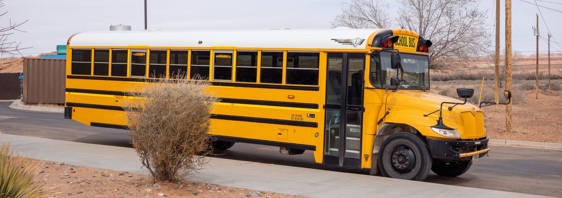 A yellow school bus parked outside the school, ready to pick up students.