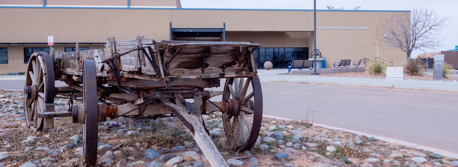 An old wooden wagon parked in front of the school, showcasing its rustic charm and historical significance.